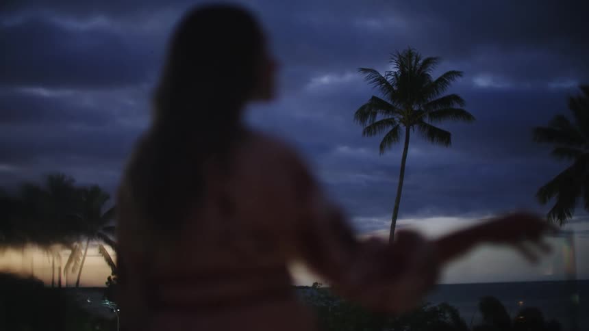 Woman standing on lanai at sunset looks like waikiki beach gazing at the distance shallow dof