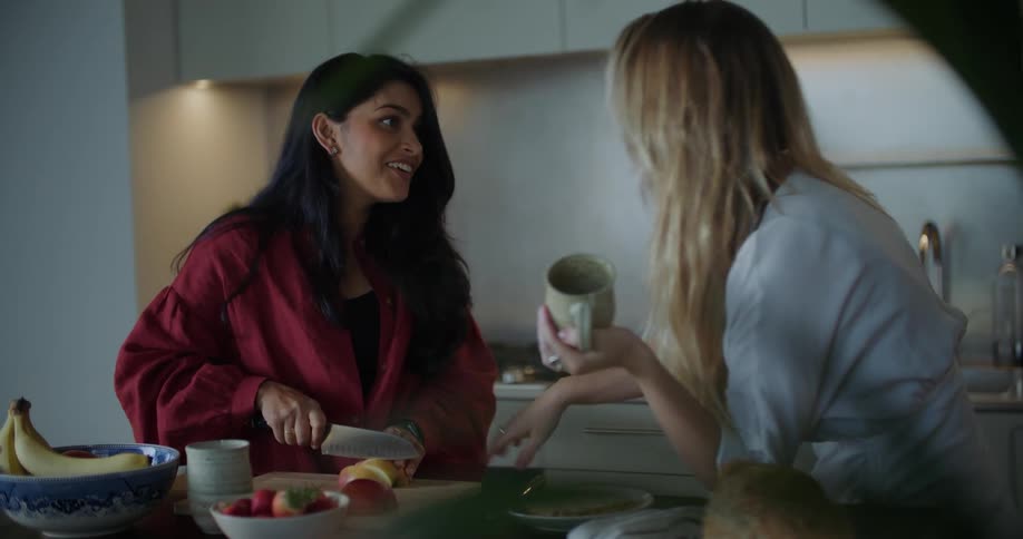 Two women laugh as one cuts food