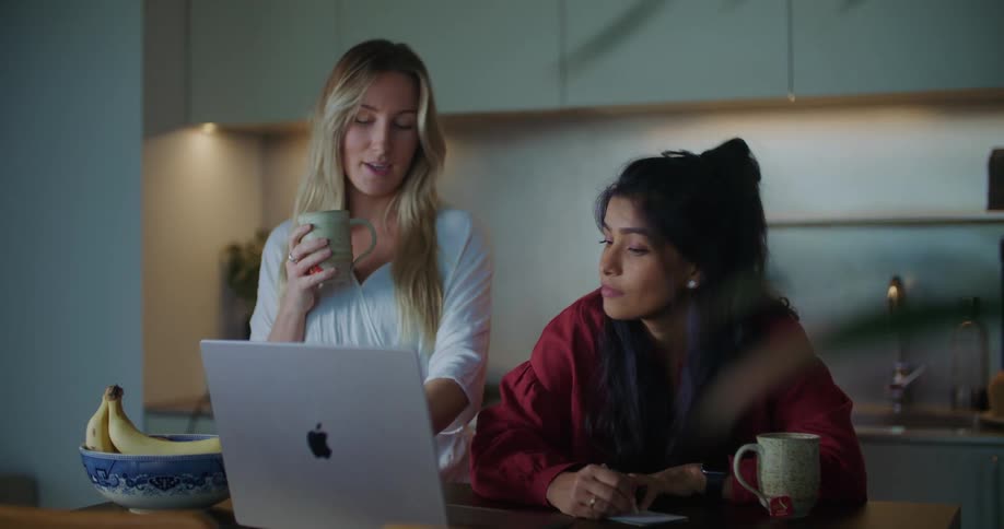 Two women talk and look at a laptop