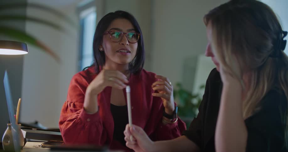 Two women sit at table with laptop smiling during a discussion