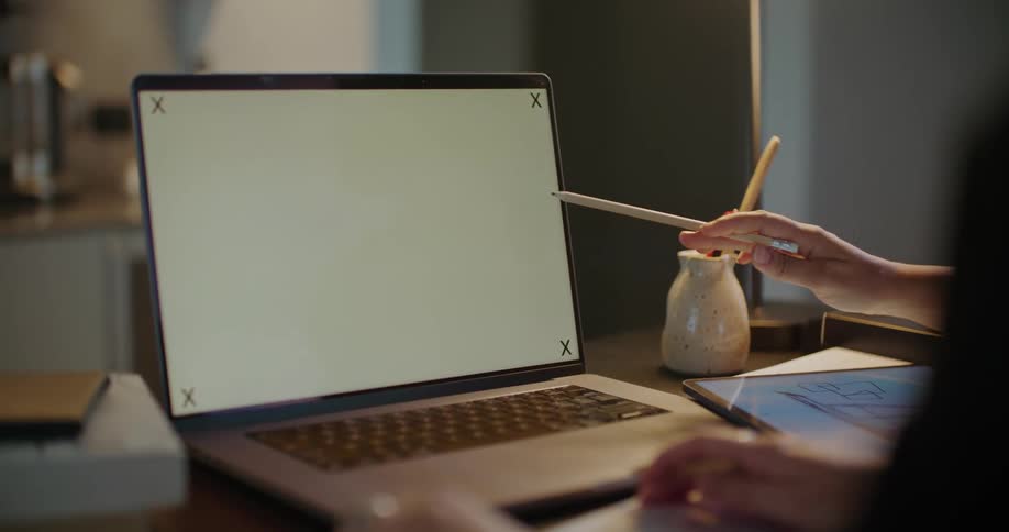 Two women sit at desk discussing contents of laptop screen