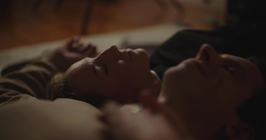 Man and woman lie on their backs in opposite directions talking with their heads together