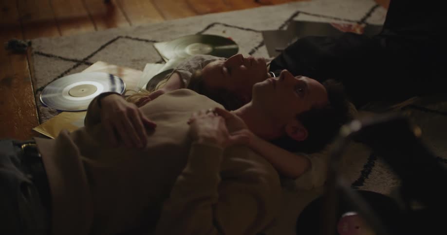 Man and woman lying together on the floor listening to records and talking