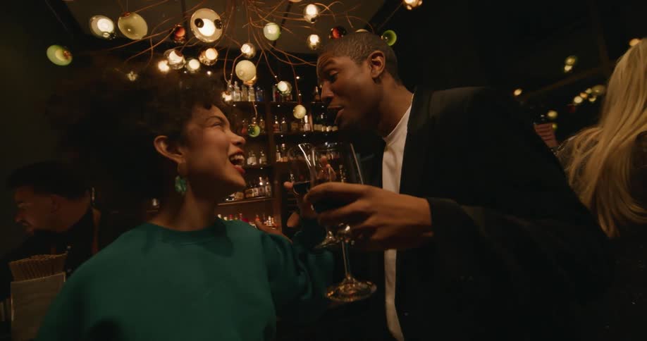 A man and woman laugh while flirting at a bar