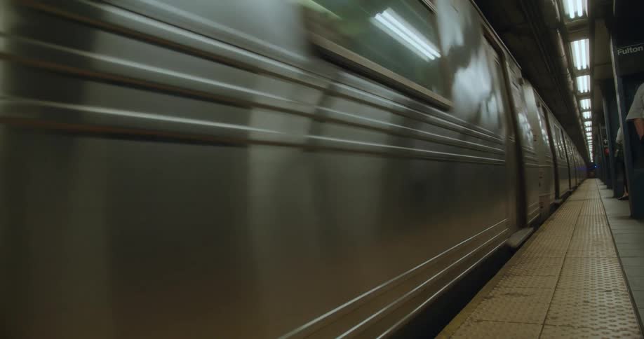 A subway is shown up close speeding down the tracks in a subway station