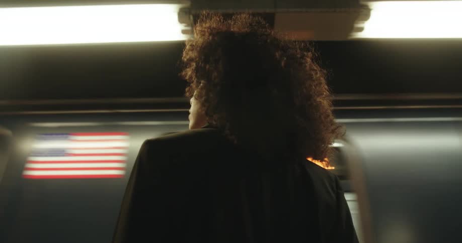 Woman standing underground in the subway station waiting for train as others pass her by