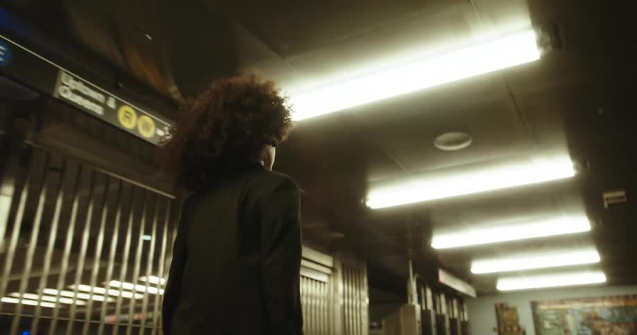 A woman in a black blazer walks in the subway station