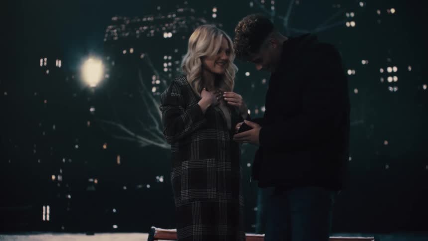 Young man and woman getting engaged at nighttime man proposes and puts ring on her finger they embrace