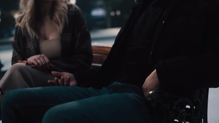 A man and woman talk on the park bench