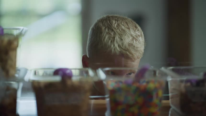 A small boy looking at candy options rubbing his head thinking