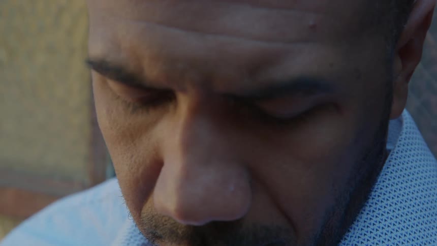 Close up of the face of a man waiting outside answer a call on his smartphone