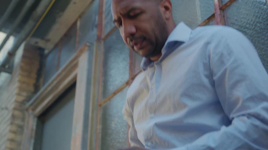 A man hangs up from a phone call and enters the building