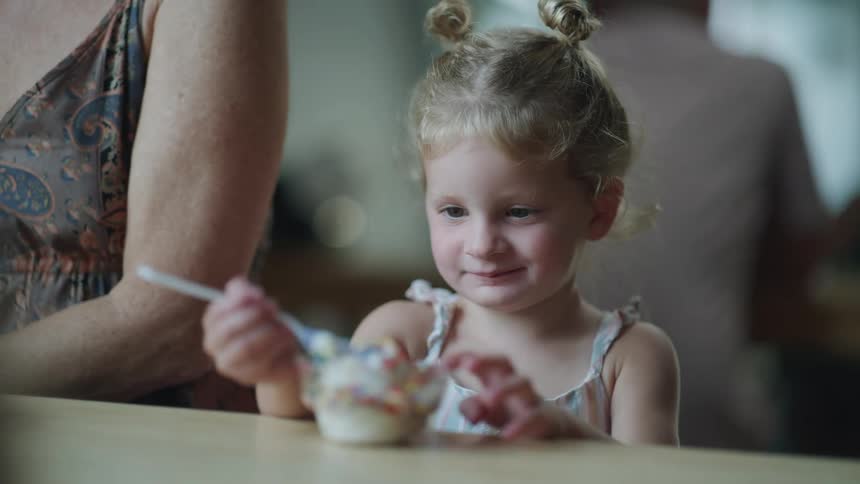 Girl smiles hesitantly while examining dessert served to her
