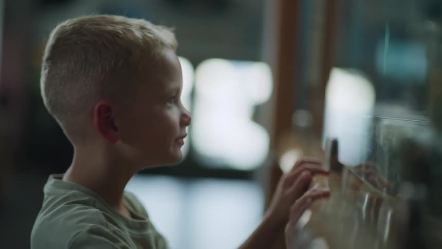 Little boy in arcade looking at the claw machine hoping to win