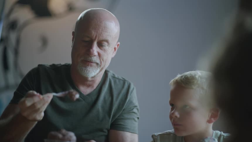 An older man and young boy sit together while eating ice cream