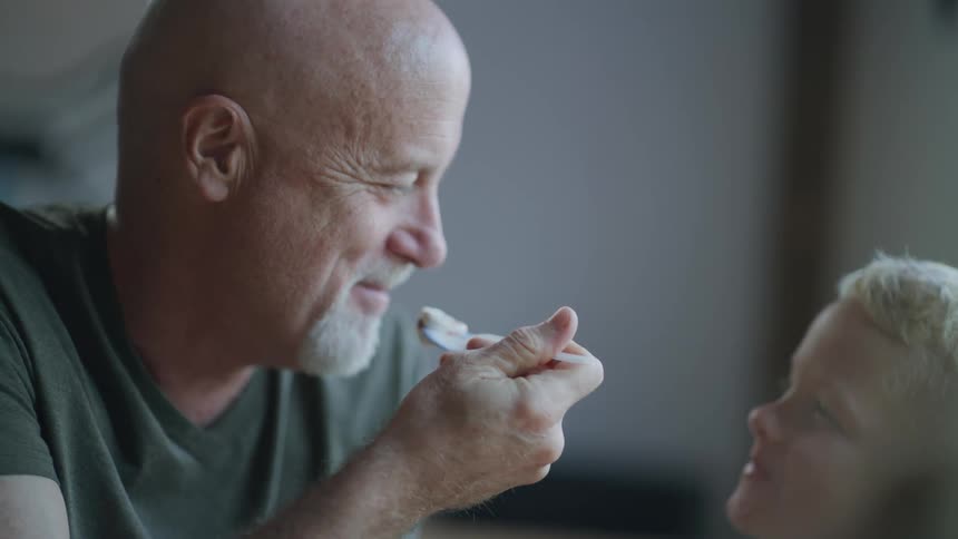 Happy father and son eat ice cream together in a restaurant at daytime