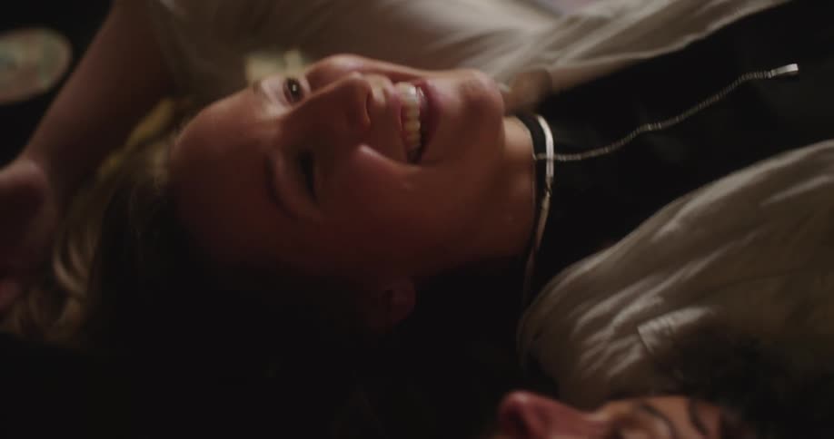 Two women lie on their backs in opposite directions and smile while talking