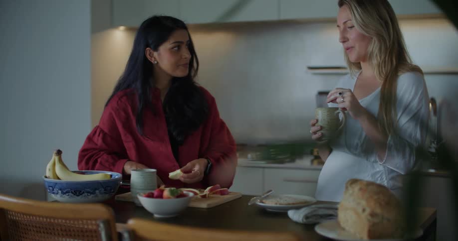 Two women chatting and laughing while one is preparing food