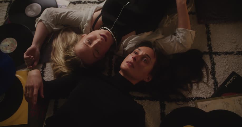 Two women are laying on carpet and talking