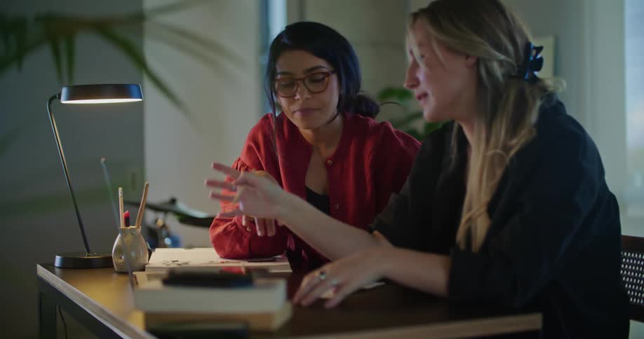 Coworkers sit at desk and discuss computer contents