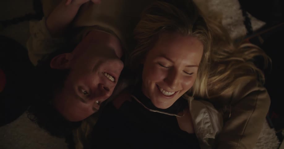 A couple lies close in opposite directions and curl arms around each other
