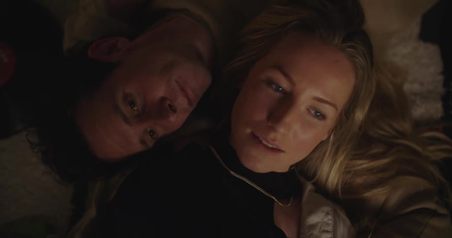 A man and woman lying on the floor together talking and listening to music smiling and having a good time