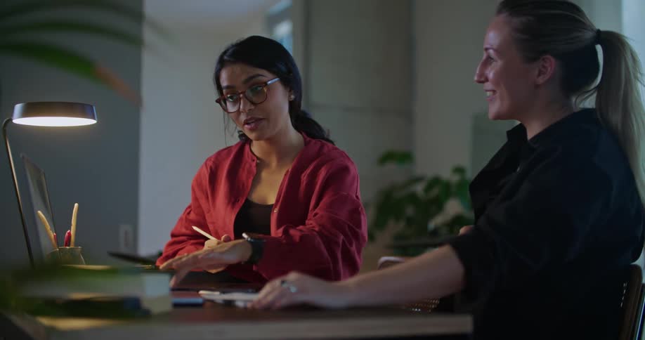 Two women talk and look at the laptop