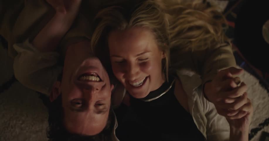 A man and woman laugh on the floor