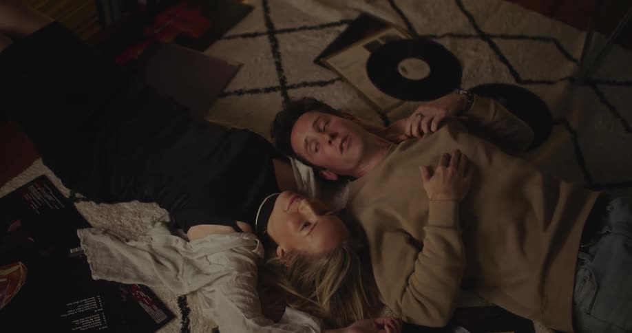 A man and woman laying on their backs on a carpet talking and smiling