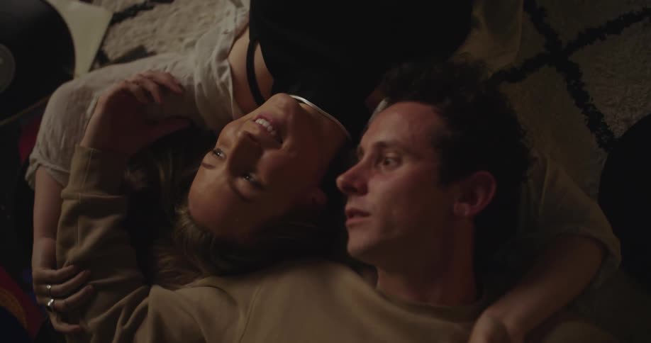 Man and woman lying on the floor together talking and listening to records at nighttime