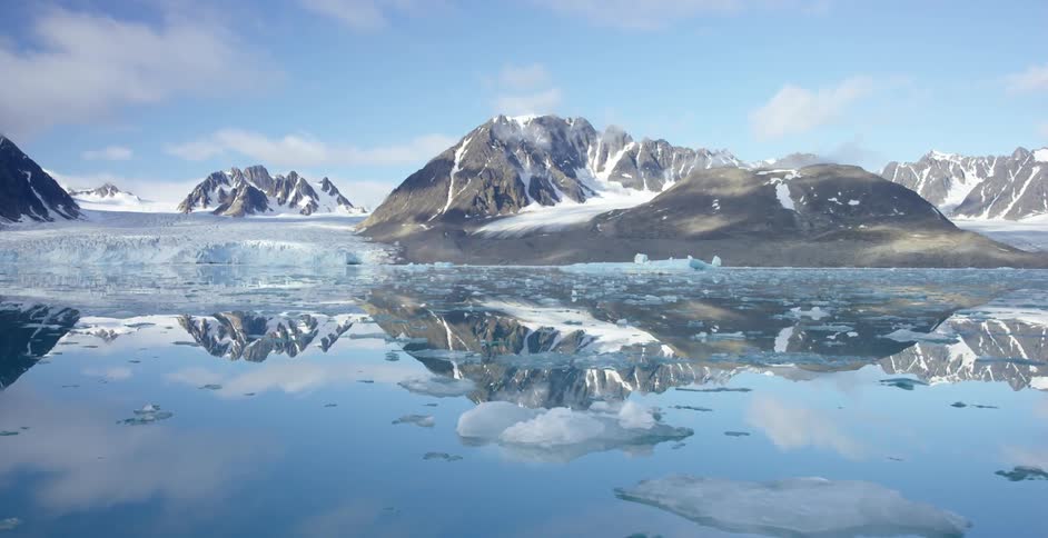Ice floating on top of clear water near snow covered mountains