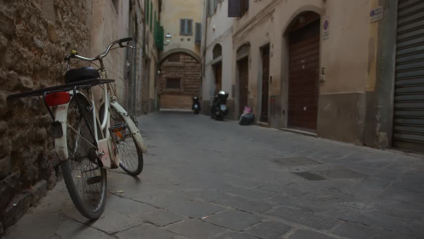 A white bicycle propped up against a stone wall on a stone alley way