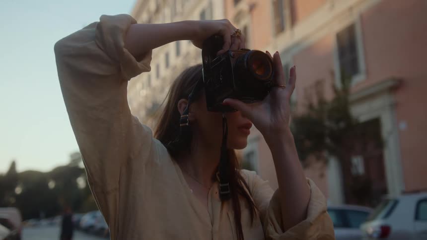 A young woman taking picture with her camera in a tourist area as she smiles