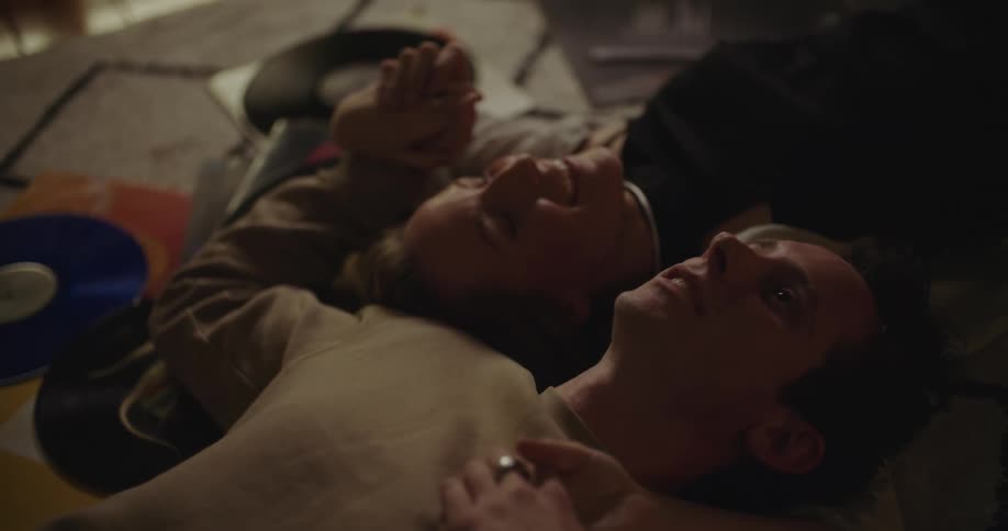 A man and woman are lying on the floor while holding hands and laughing with each other