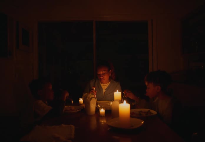 Mother and young boys eating dinner by candlelight at night