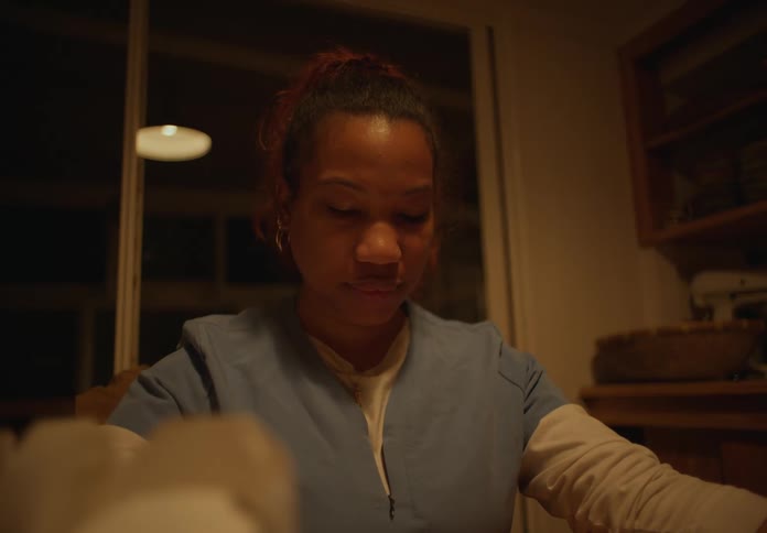 A woman says grace while sitting at her kitchen table