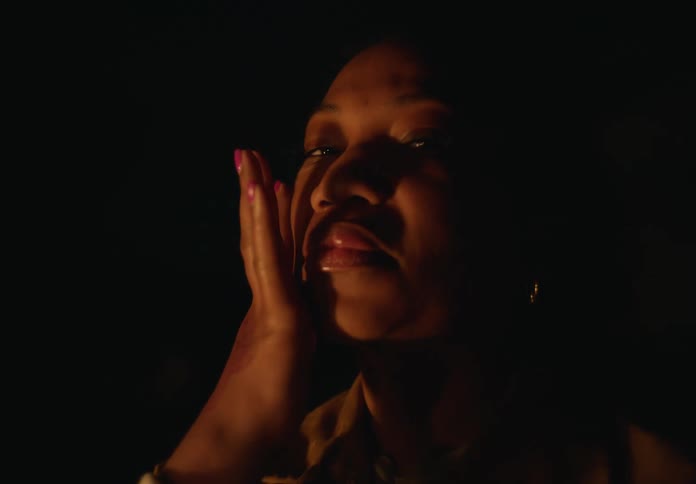 A close up of a womans face as she runs her hand across it