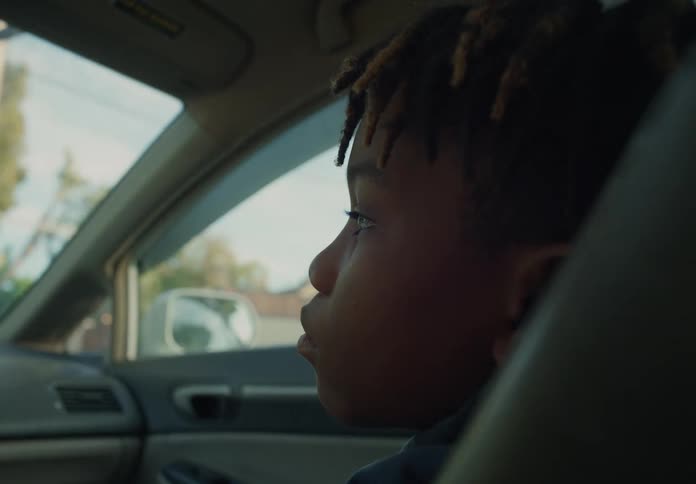 Boy with dreadlocks sits in car driving on highway