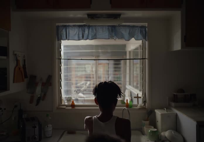 A young boy washing at the kitchen sink talking when his little brother jumps up and drinks from the faucet