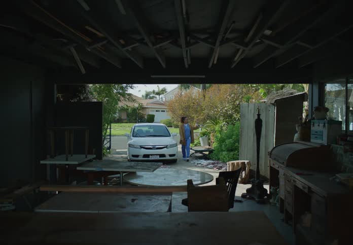 A woman walking up a driveway into her garage