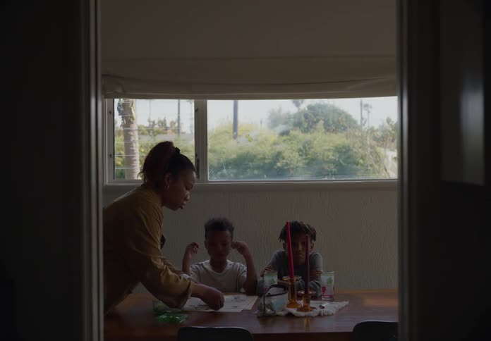 A woman interacts with two boys sitting at a dining table under a window