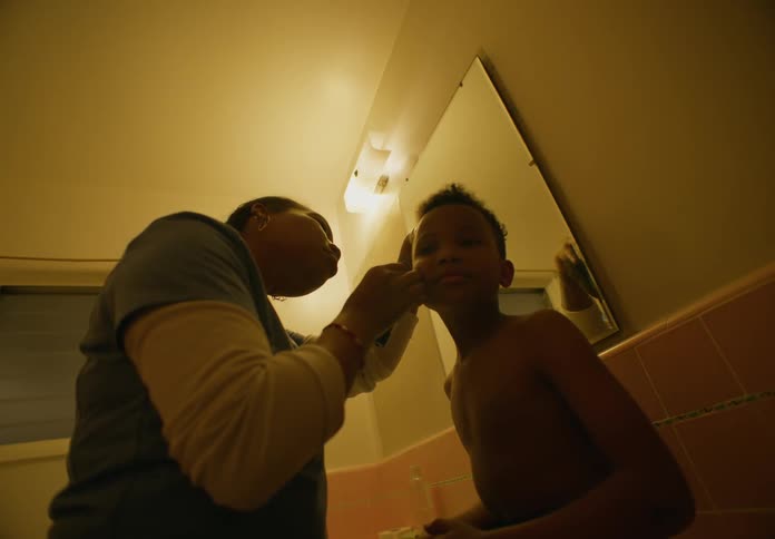 Mother trimming the hair on her son head in the bathroom