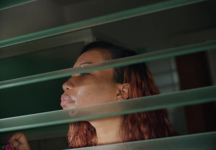 A woman is peering out the window