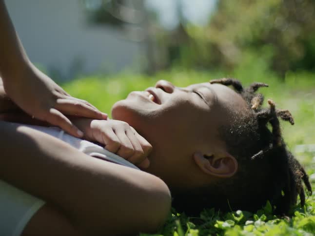 Boy lies on his back on ground while playing with a friend
