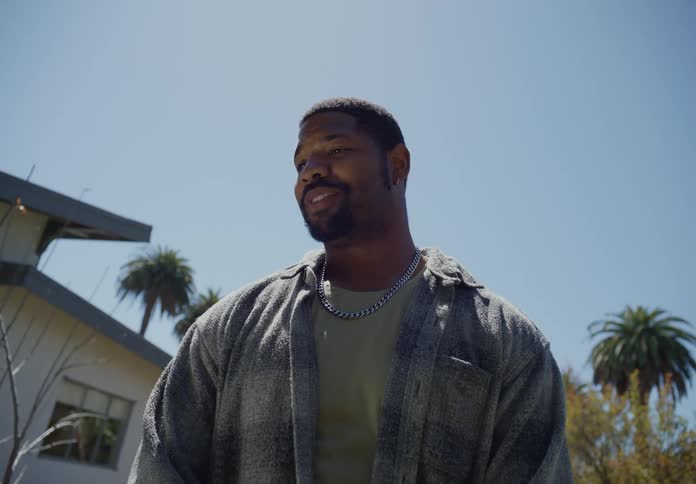 Man standing in the backyard at home talking to someone under a blue sky