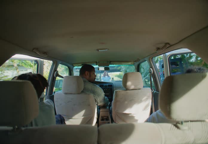 Two young boys exit the family car and run towards a female waiting for them