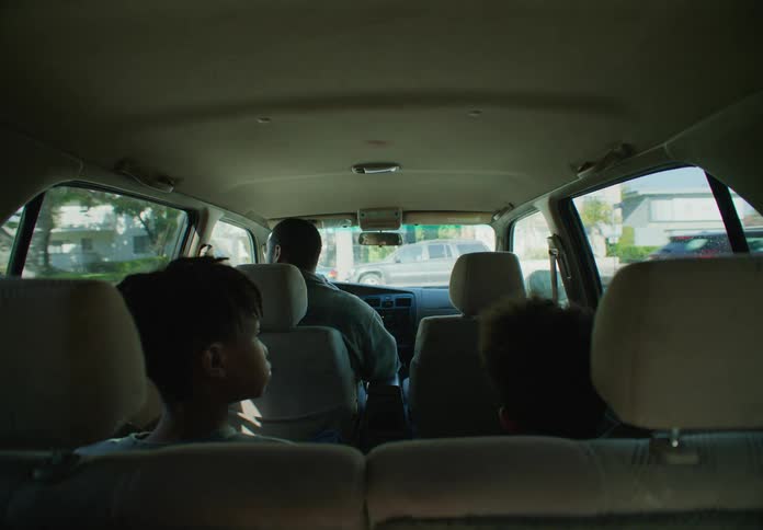 Brothers ride in back seat as the car their father is driving pull up to an intersection