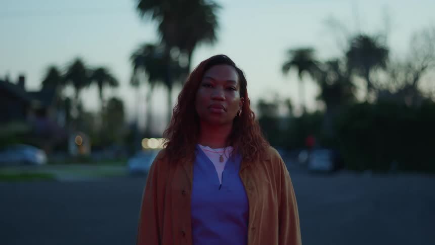 Woman stands in culdesac road in a residential neighborhood after dusk