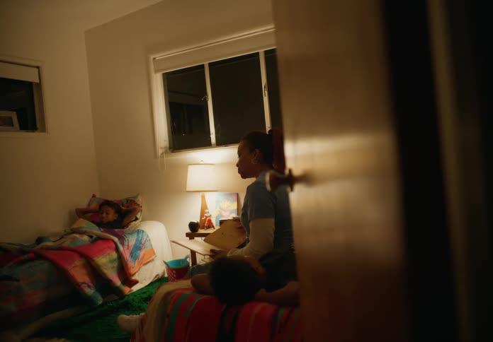 Mother sits in bedroom and reads to her sons at night