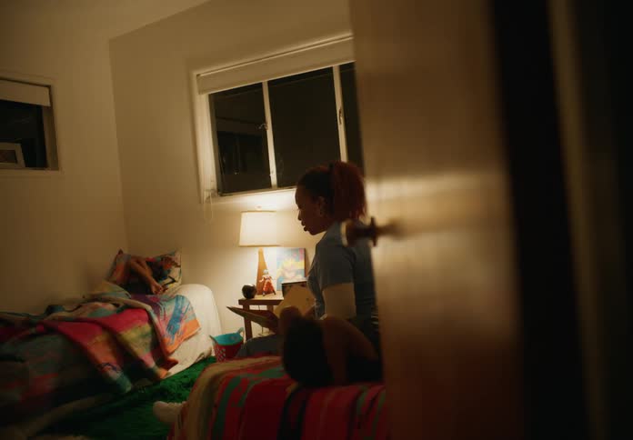Mother sits on bed reading from a book to her sons at bedtime